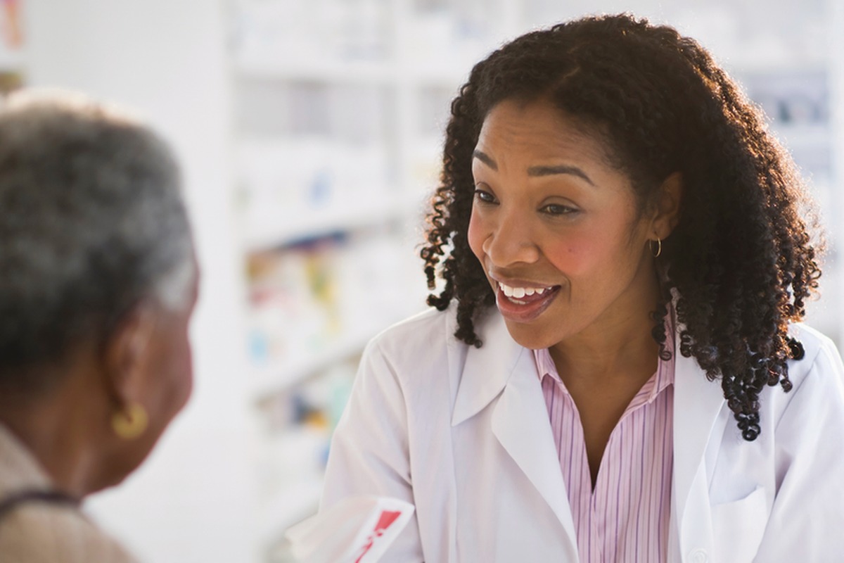 A pharmacist talking with a customer at a retail pharmacy counter