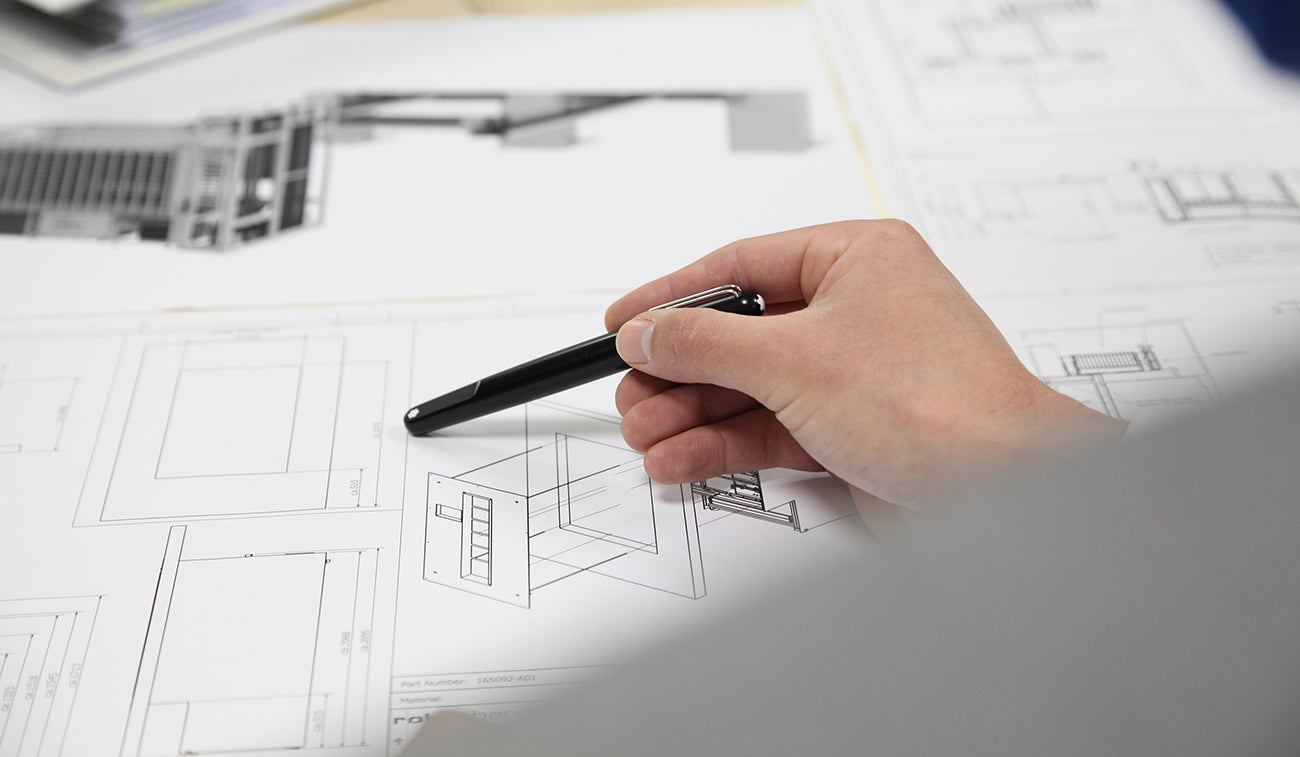 A hand marking up CAD elevations of RoboPharma equipment